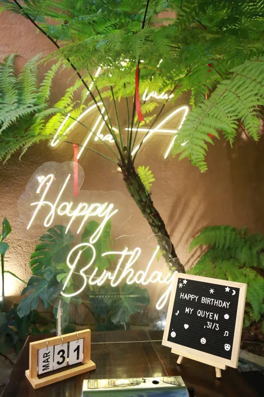 Góc check-in với đèn neon Nhà An và Happy Birthday giữa vòm cây dương xỉ