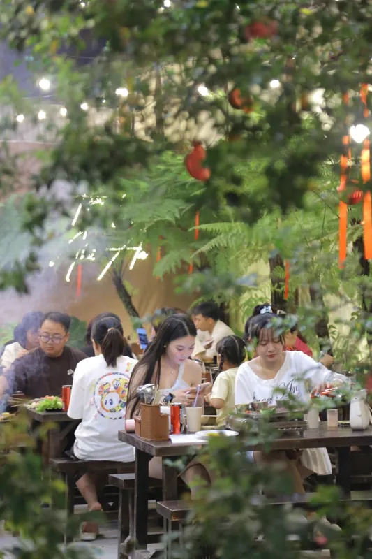 Bàn ăn đặt giữa vòm cây xanh trong quán