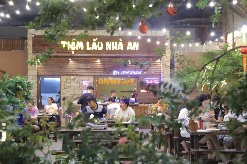 Mặt tiền Tiệm Lẩu Nhà An buổi tối với đèn dây và biển hiệu