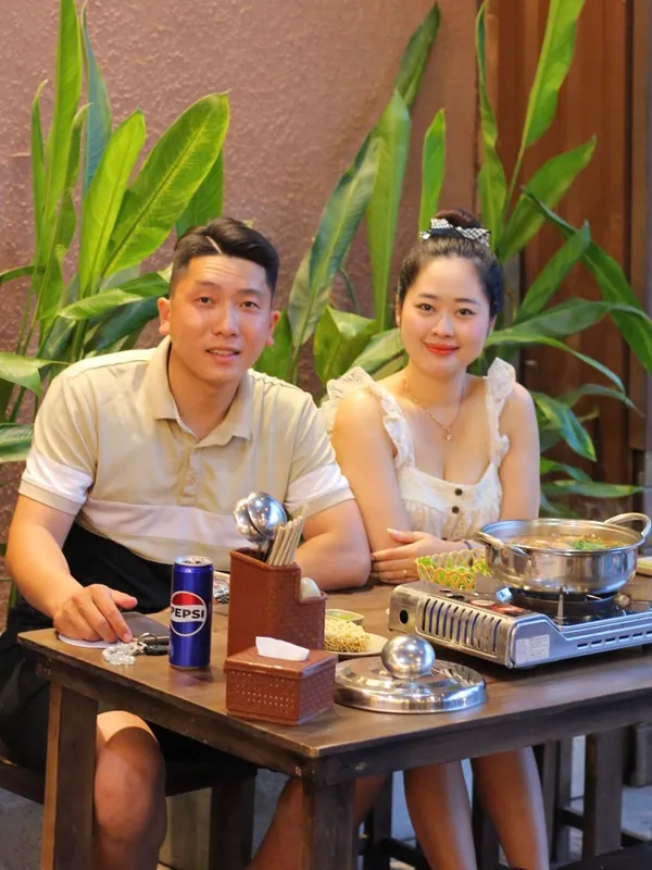 Cặp đôi ngồi ăn tối bên bàn lẩu tại quán