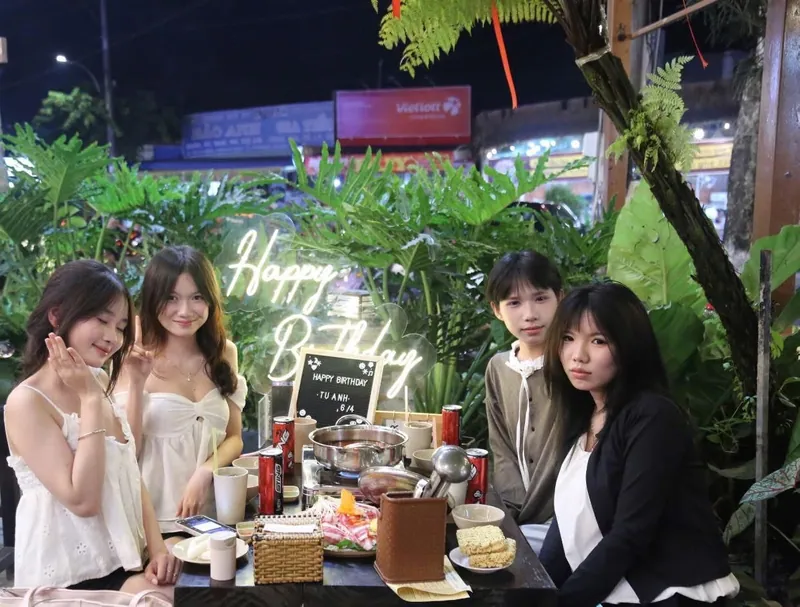 Nhóm bạn tổ chức tiệc sinh nhật bên bàn lẩu có đèn neon chúc mừng